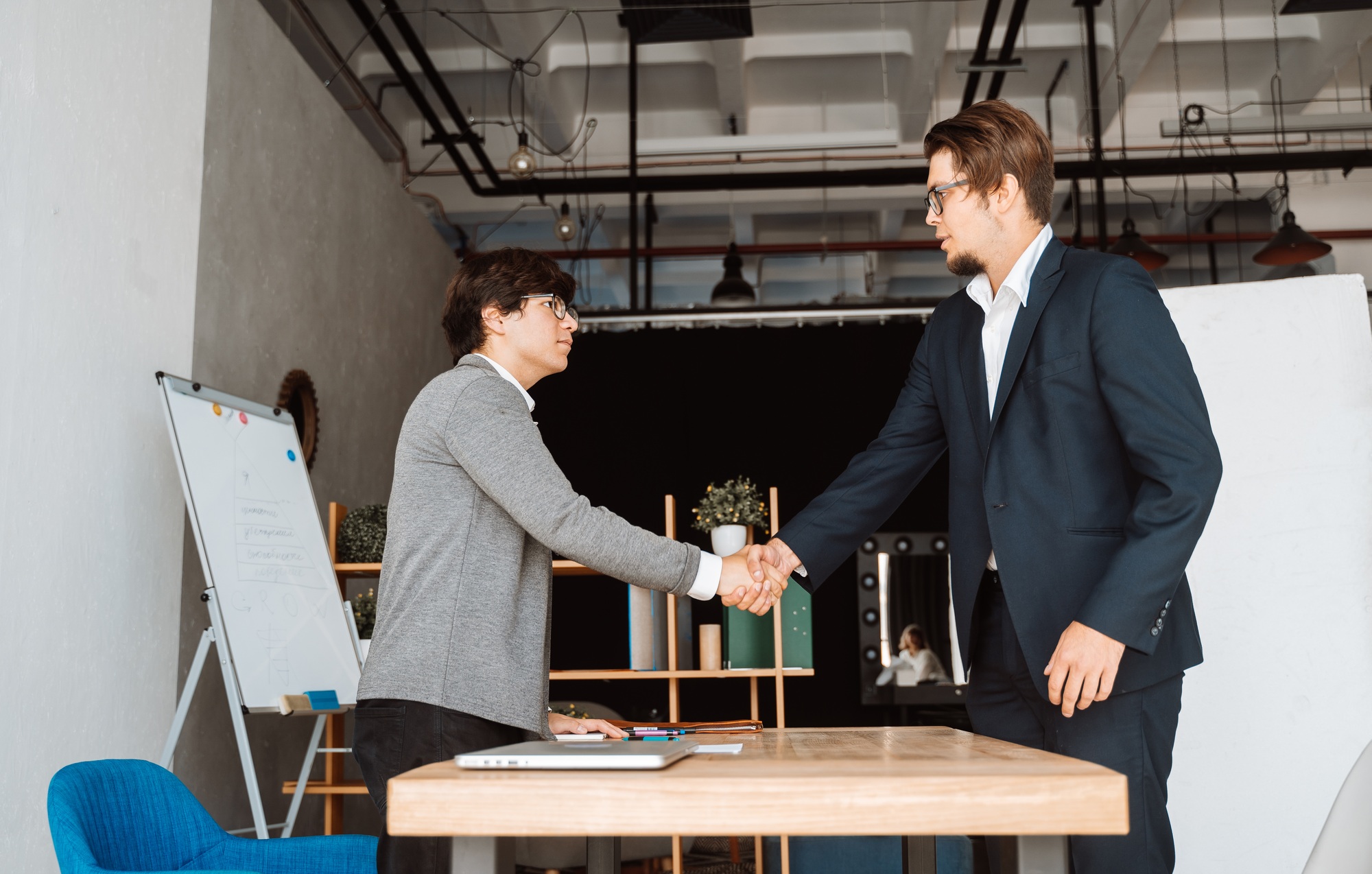 Two happy satisfied businessmen shaking hands over